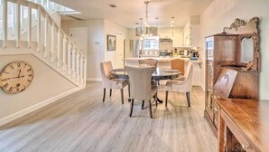 A dining area with a round table and chairs, a wooden cabinet, and a staircase with white railings. - Horseshoe Bay Townhome w/ Patio & Outdoor Pool! (Horseshoe Bay)