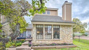 A stone house with a stone facade, a chimney, and a small porch with outdoor seating. - Horseshoe Bay Townhome w/ Patio & Outdoor Pool! (Horseshoe Bay)
