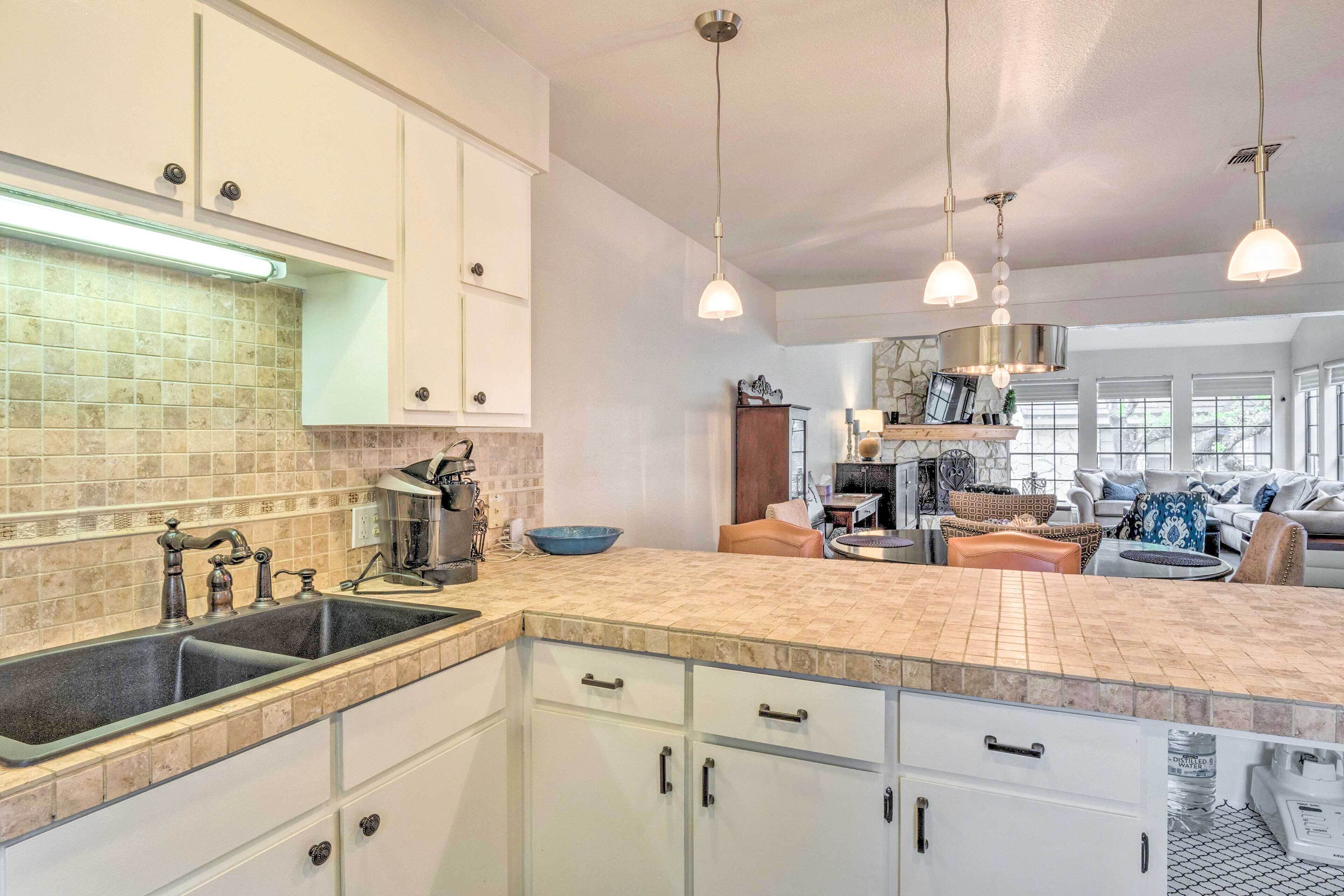 A spacious kitchen with a large island, white cabinetry, and pendant lighting.