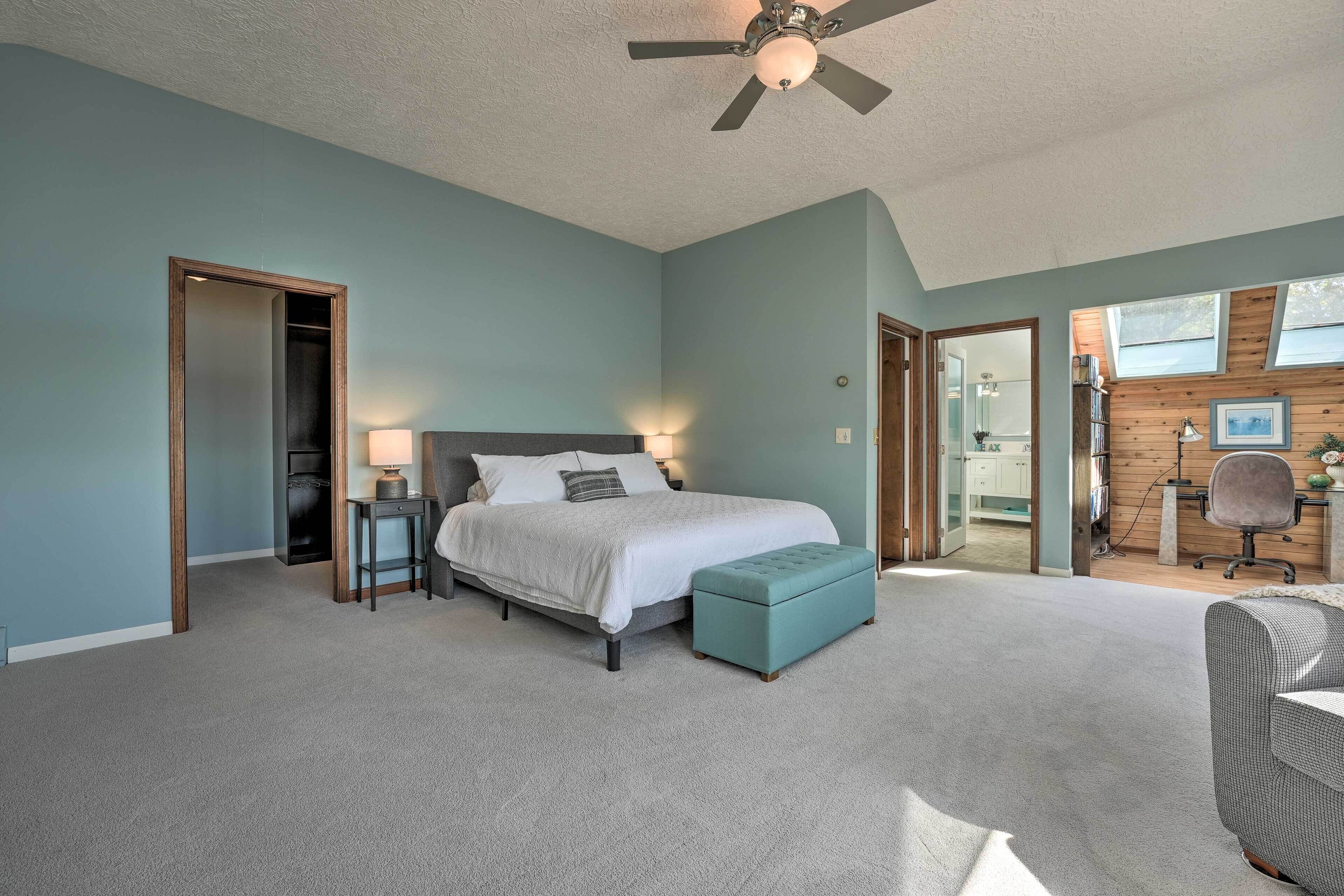 A bedroom with a bed, a desk, a chair, and a ceiling fan.