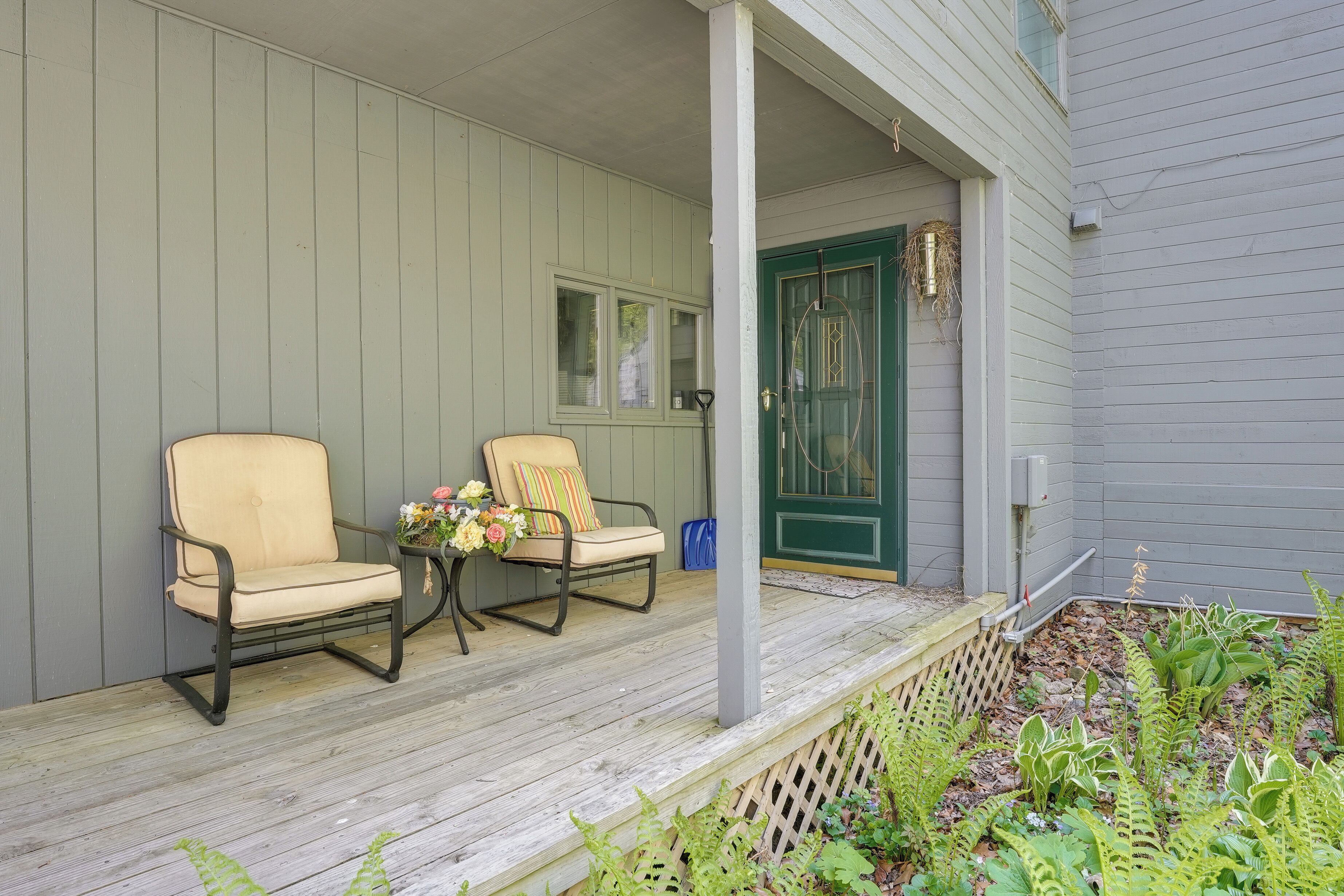 A porch with two chairs and a small table with flowers.