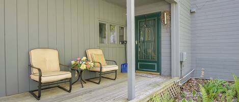 A porch with two chairs and a small table with flowers.