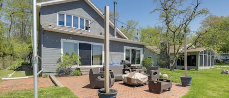 A two-story house with a brick patio, outdoor furniture, and a covered grill area.