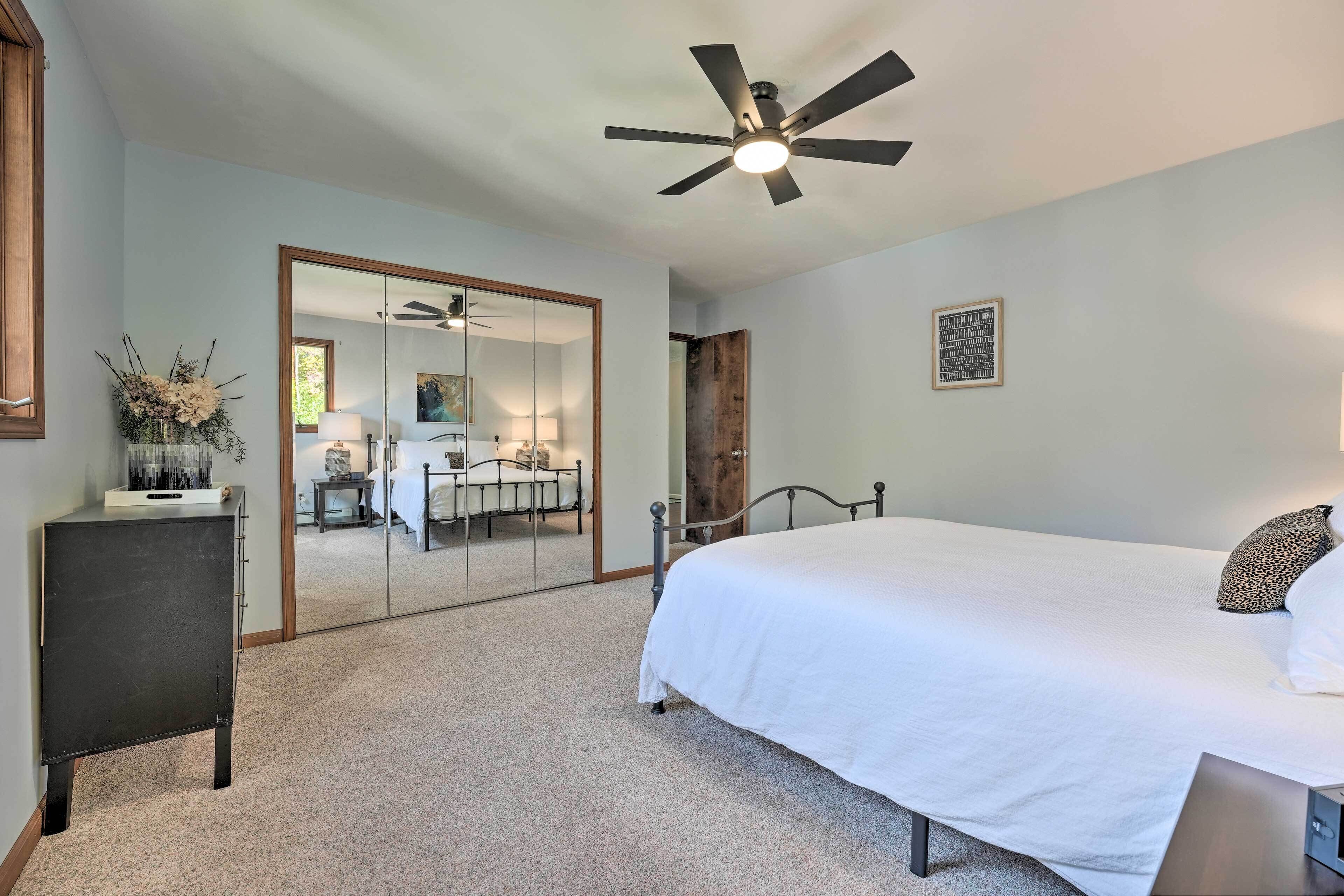 A bedroom with a bed, a ceiling fan, a dresser, and a mirror.