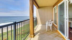 A balcony with a view of the ocean, a tiled floor, and a white chair. - Lincoln City Oceanfront Condo, Near Lincoln Beach! (Gleneden Beach)