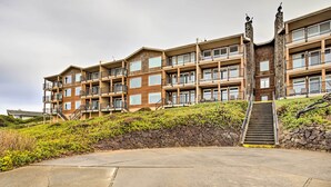 A multi-story hotel with balconies, a stone retaining wall, and a staircase leading to the entrance. - Lincoln City Oceanfront Condo, Near Lincoln Beach! (Gleneden Beach)