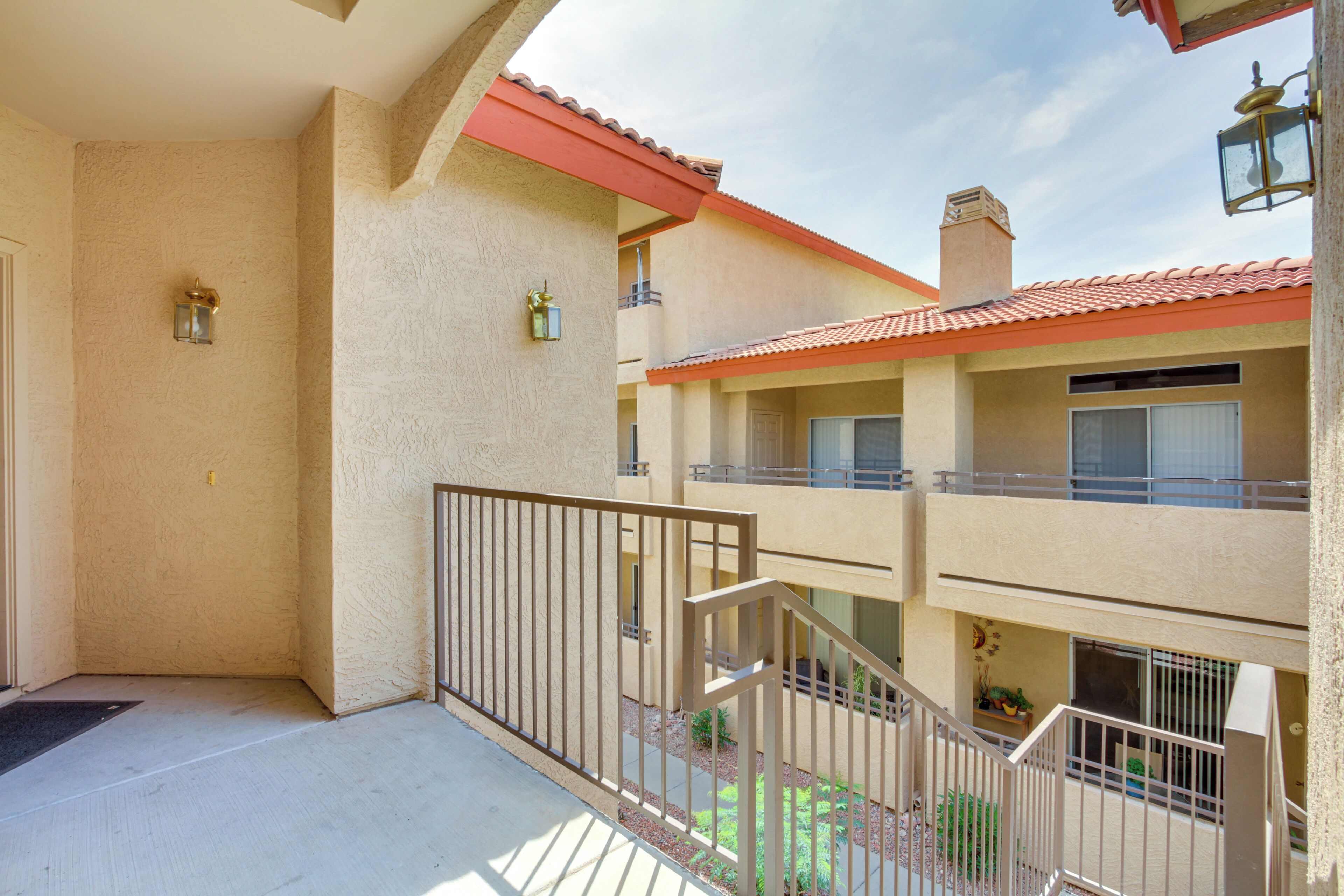 A multi-story building with balconies, a red-tiled roof, and a beige exterior.