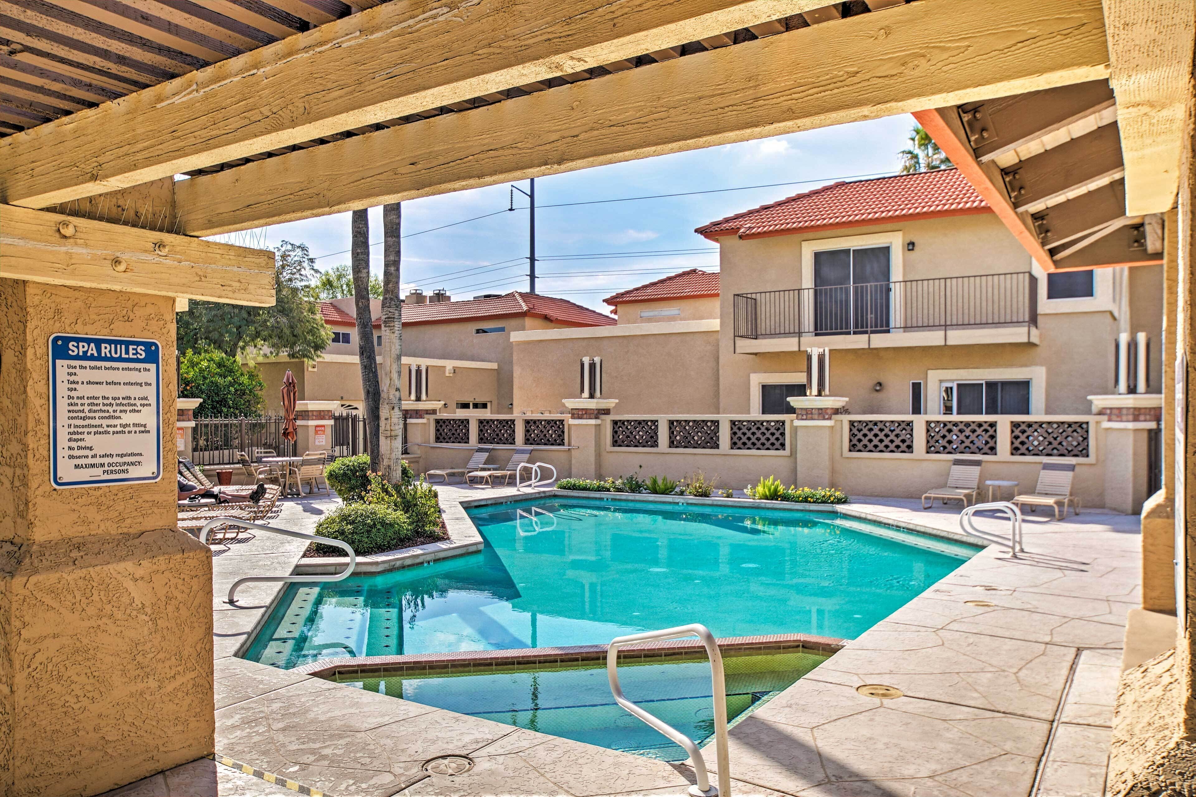 A pool area with a sign detailing spa rules, lounge chairs, and a clear view of the surrounding buildings.