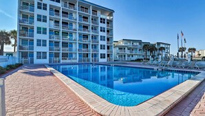 Um hotel com várias varandas, uma piscina e um céu azul límpido.