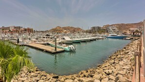 A marina with boats docked, rocky shoreline, and buildings in the background. - Upscale Cabo Home w/ Jacuzzi, Above Puerto Paraiso (Cabo San Lucas)
