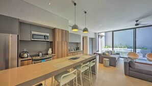 A modern kitchen with a central island, bar stools, and a dining area with a sofa and chairs. - Upscale Cabo Home w/ Jacuzzi, Above Puerto Paraiso (Cabo San Lucas)