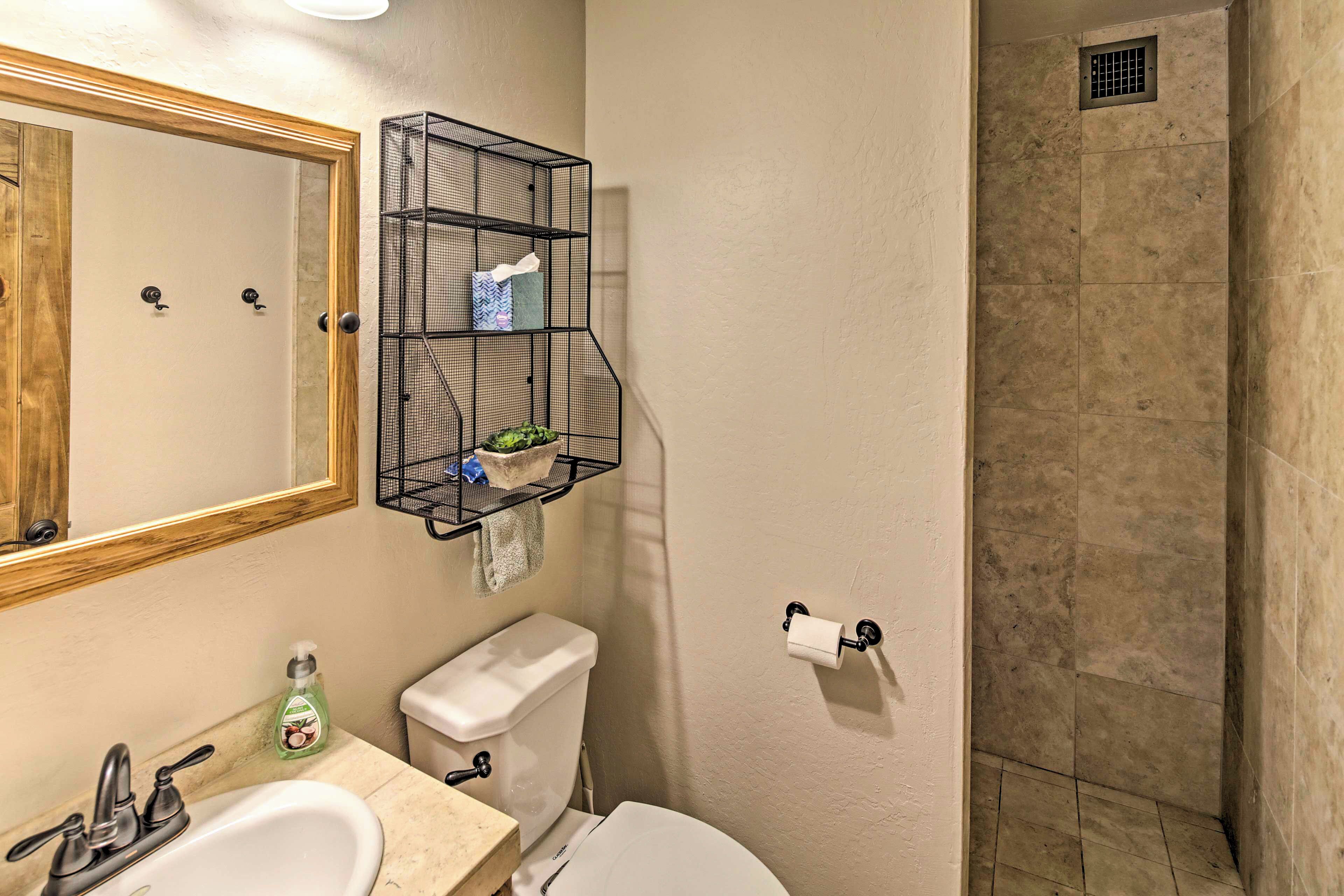 Un baño con lavamanos, inodoro, espejo y zona de ducha.