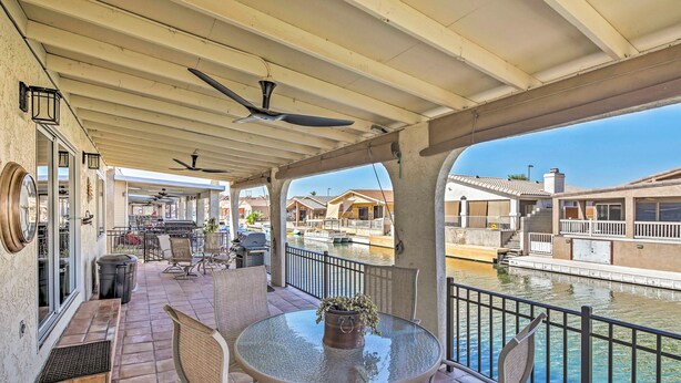 A covered patio with a table and chairs, a potted plant, and a view of a canal with boats. - Waterfront Home in Parker w/ Mtn Views & Dock! (Parker)