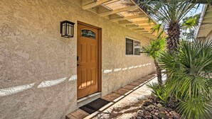 A stucco exterior with a wooden door, a small window, and a palm tree. - Waterfront Home in Parker w/ Mtn Views & Dock! (Parker)