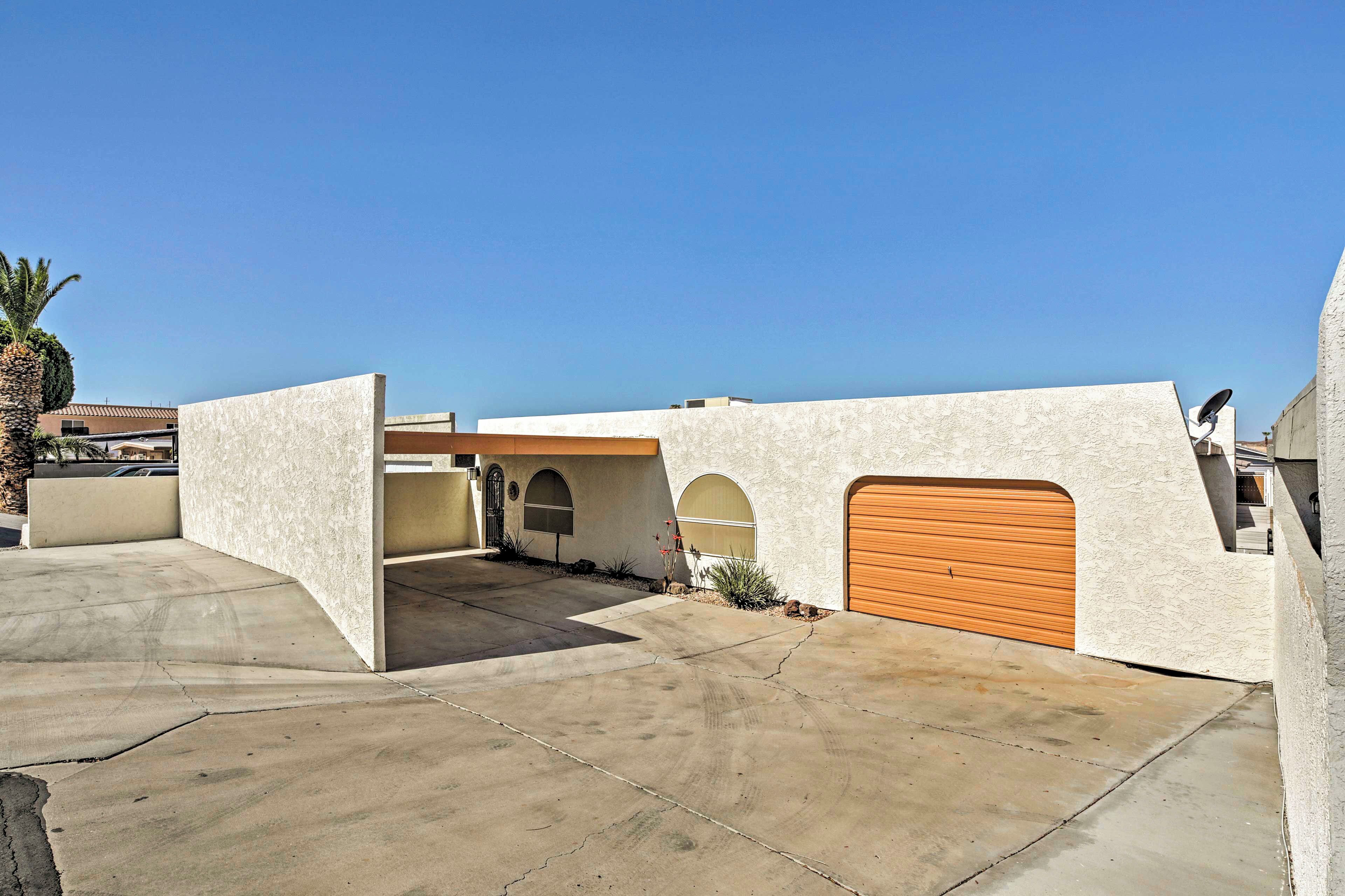Une maison moderne avec un garage, une allée et un ciel bleu dégagé.
