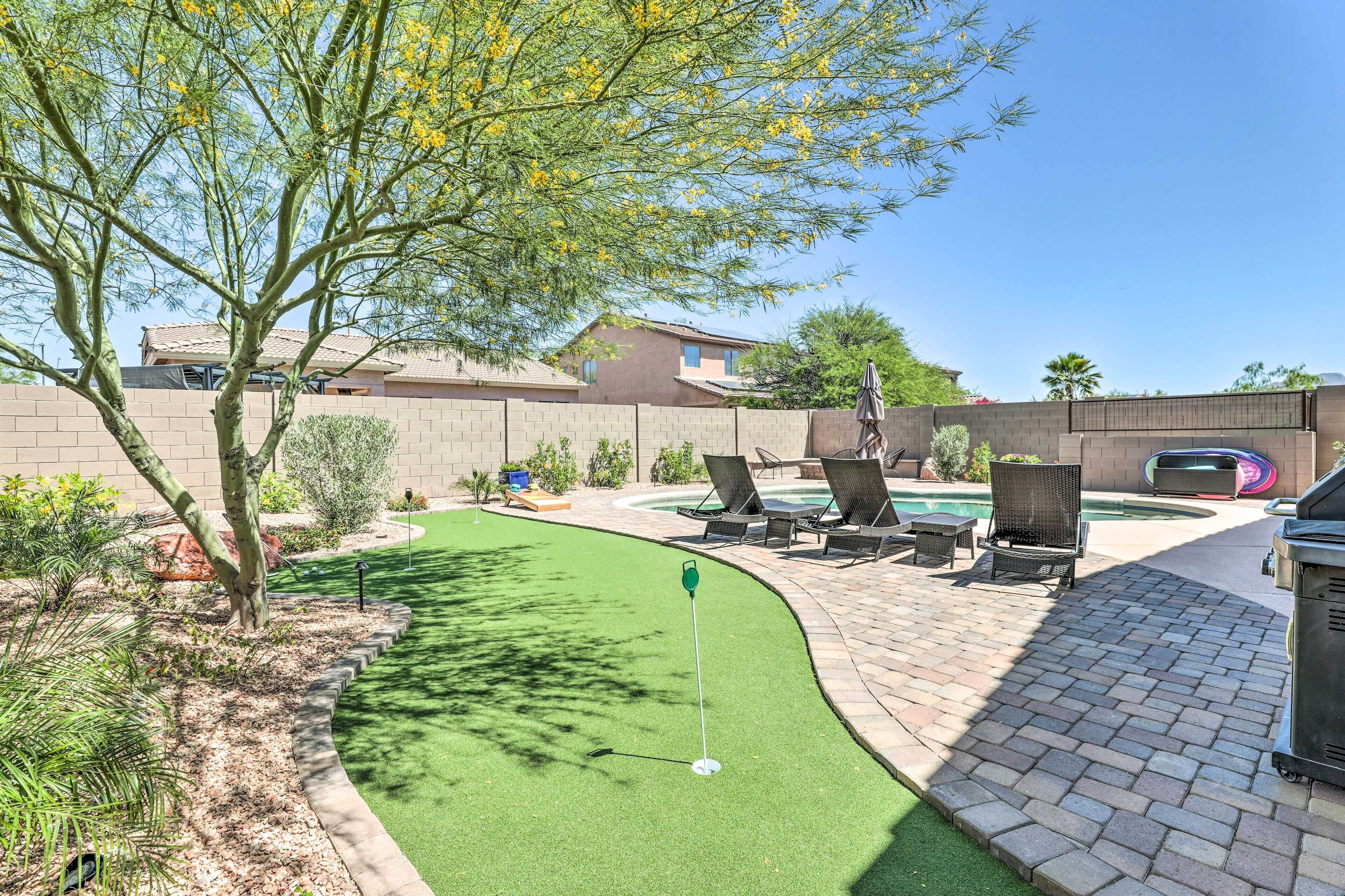 A backyard with artificial turf, a pool, and outdoor furniture.