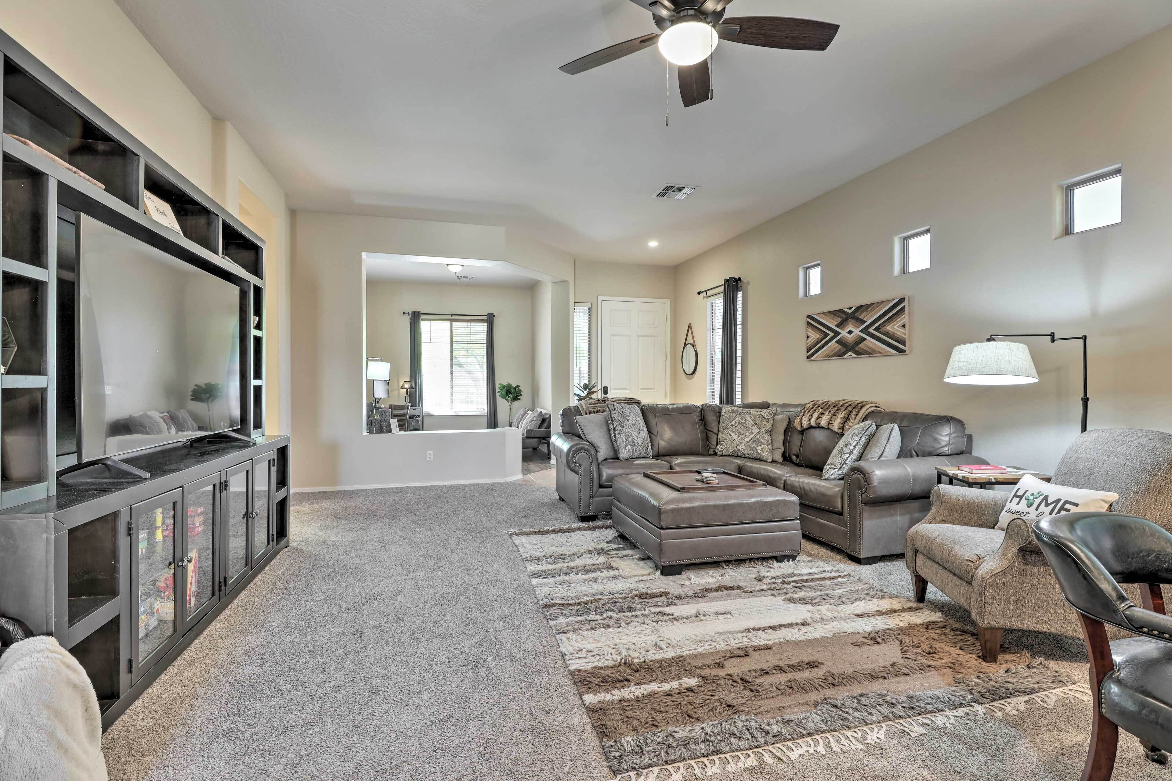 A spacious living room with a large sectional sofa, a coffee table, and a TV on a black entertainment unit.