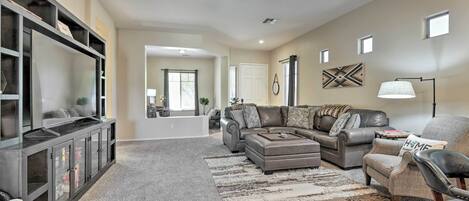 A spacious living room with a large sectional sofa, a coffee table, and a TV on a black entertainment unit.