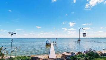 A wooden dock extending into a calm lake with a small boat and a gazebo.
