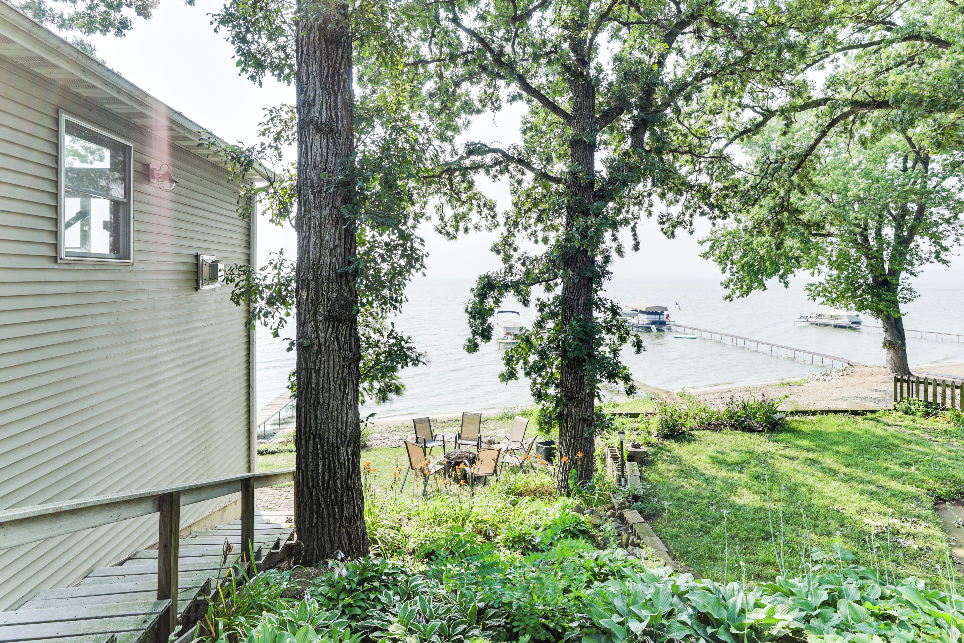 A house with a deck overlooking a lake, featuring a table and chairs for outdoor dining.