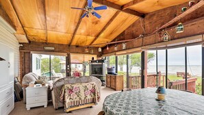 Een knus chalet met houten plafond, een groot raam met uitzicht op een meer, een eettafel en een comfortabele zithoek.