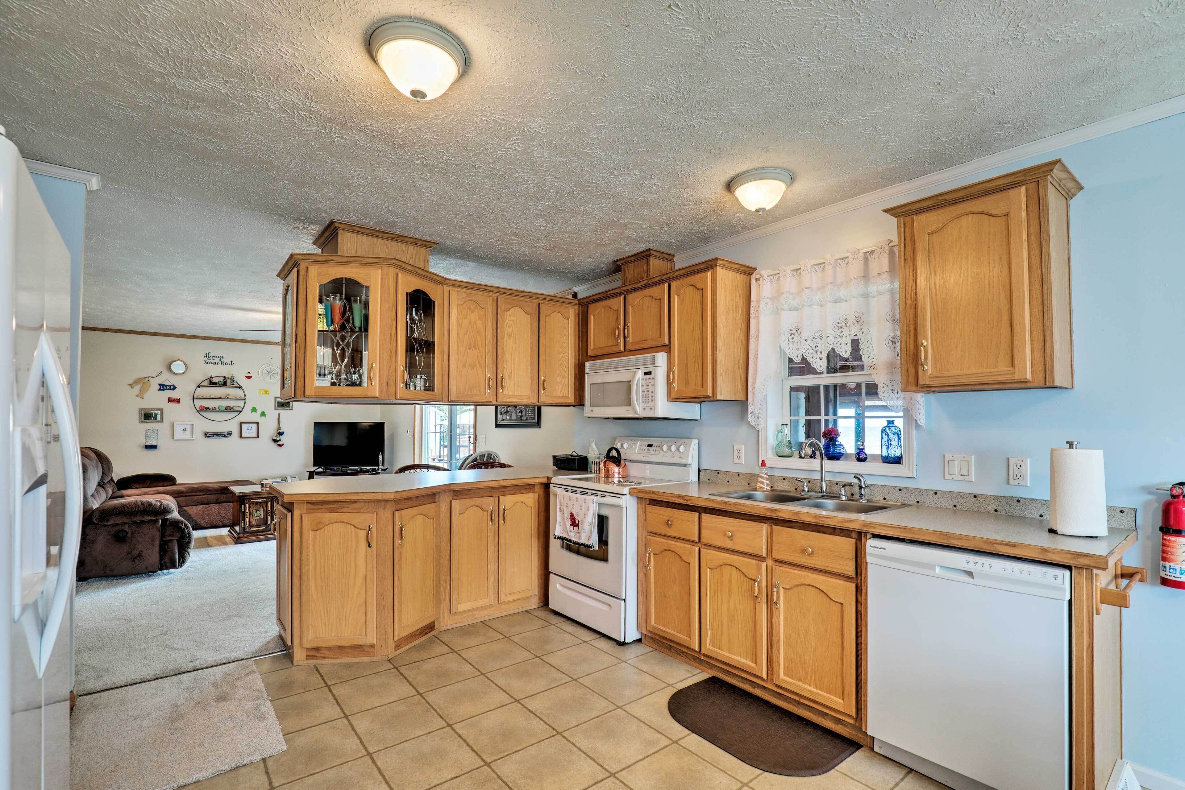 A kitchen with wooden cabinets, a white stove, a microwave, and a dishwasher.