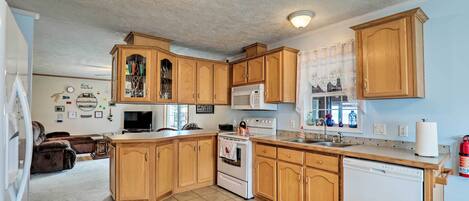 A kitchen with wooden cabinets, a white stove, a microwave, and a dishwasher.