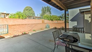 A covered patio with a table and chairs, a brick wall, and a view of the neighborhood. - Green Valley Townhome w/ Patio & Resort Amenities (Green Valley)