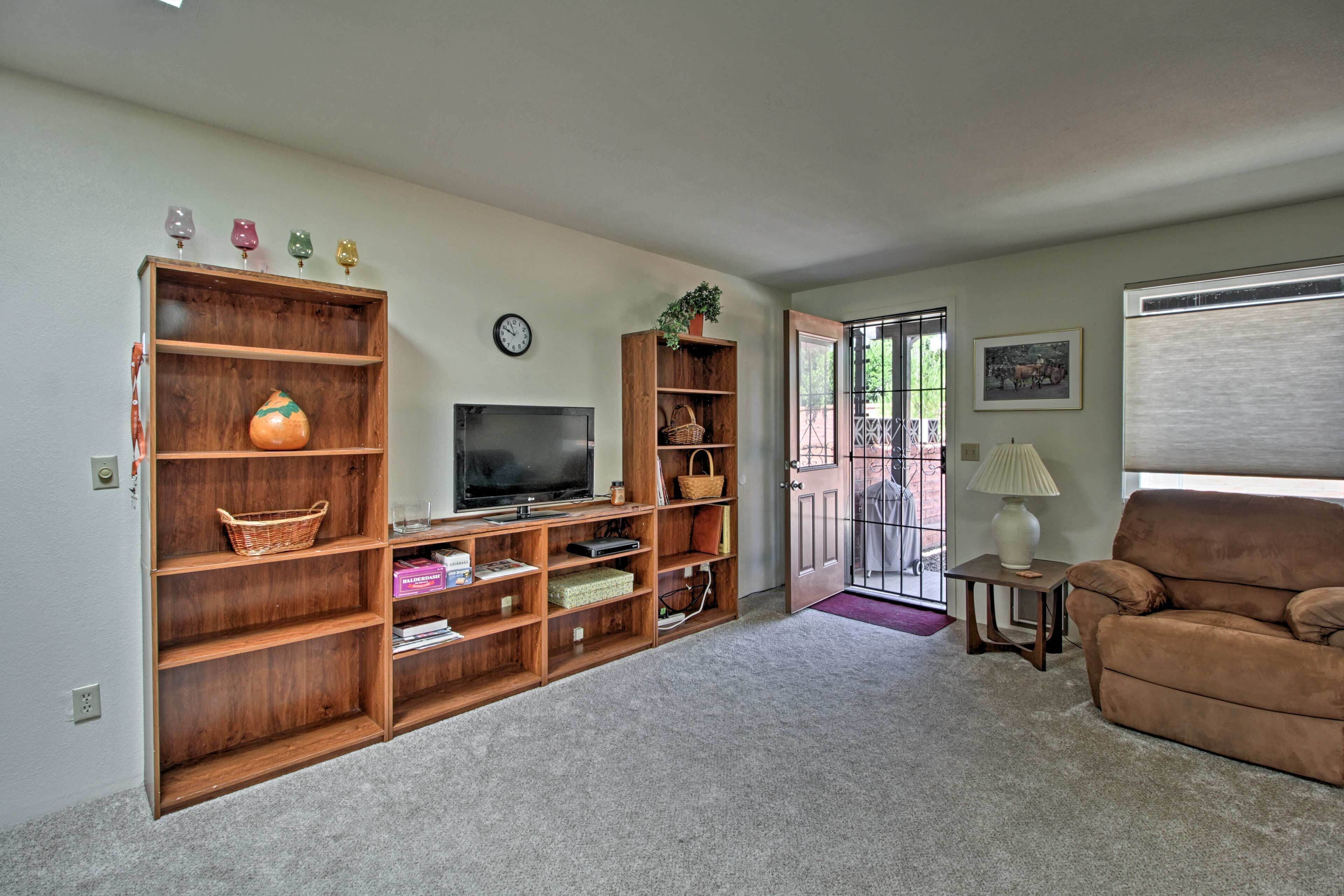 A living room with a TV, wooden shelving, a brown sofa, and a door leading outside.