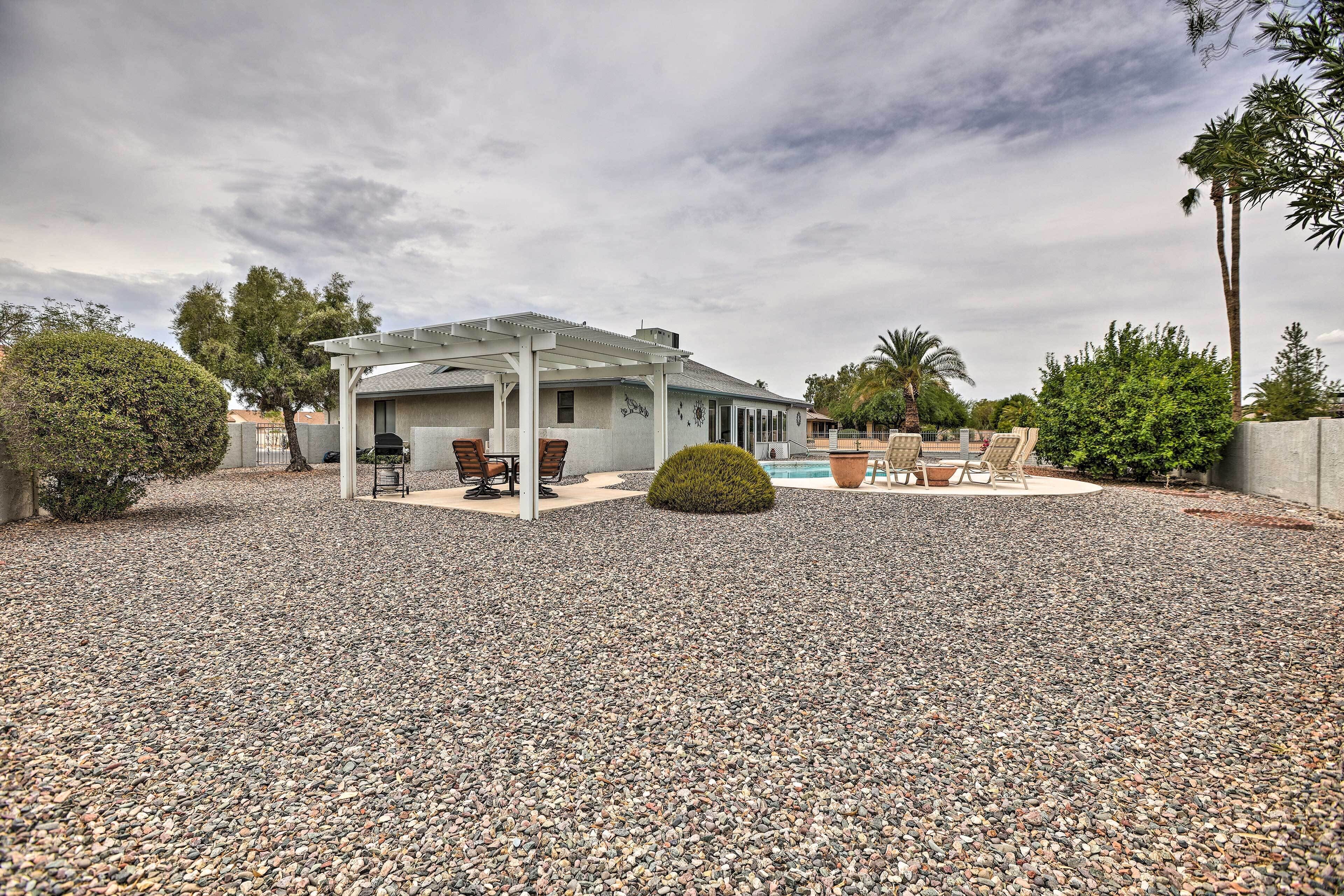 Un patio cubierto con mobiliario exterior, piscina y suelo de grava.
