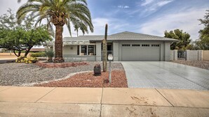 A modern two-story house with a garage, a well-maintained garden with palm trees, and a paved driveway. - 1 Mi to Golf! Family-friendly Sun City West Home (Sun City West)