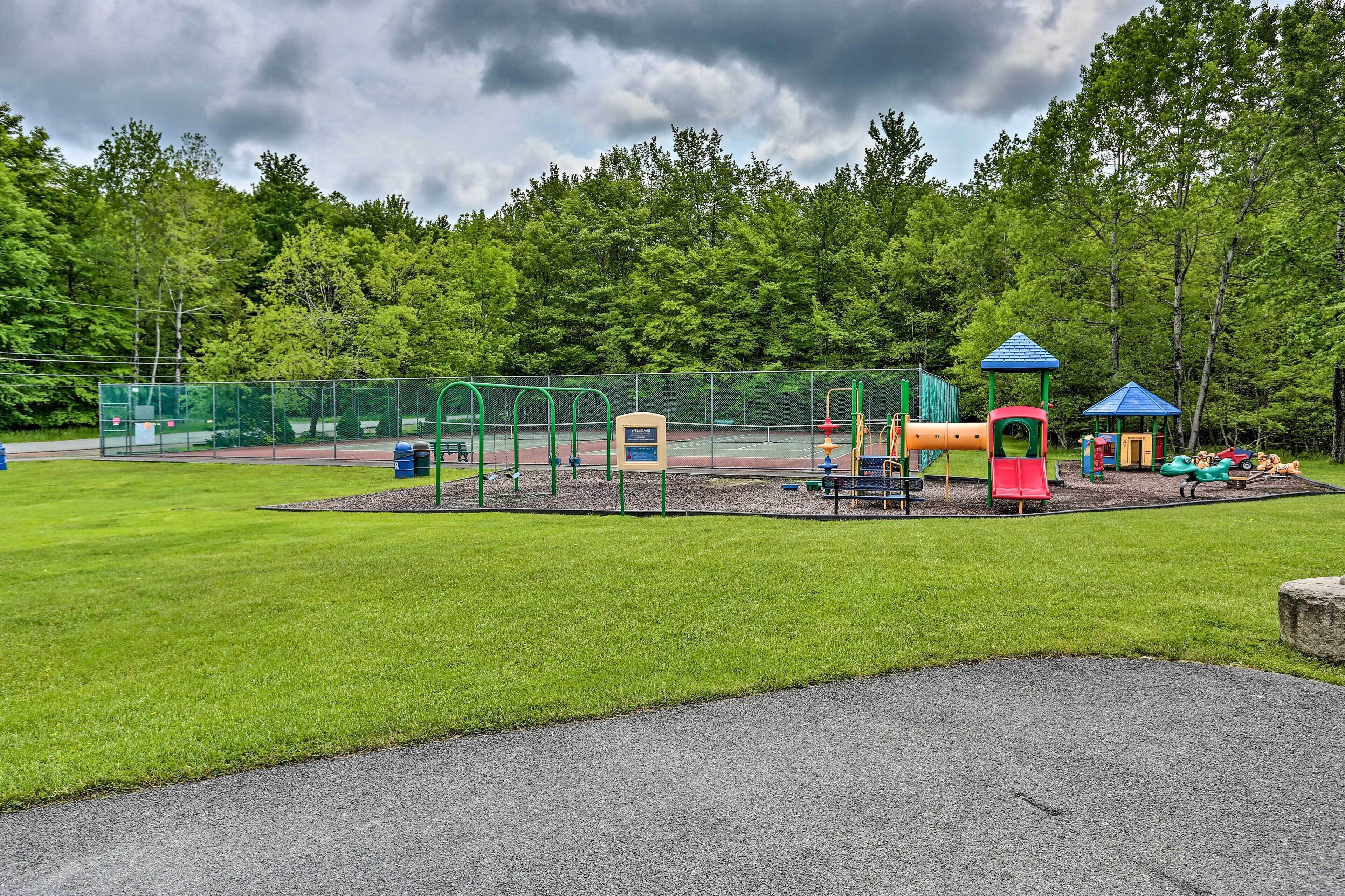 Un parque infantil con diversas estructuras de juego, rodeado de césped y árboles.