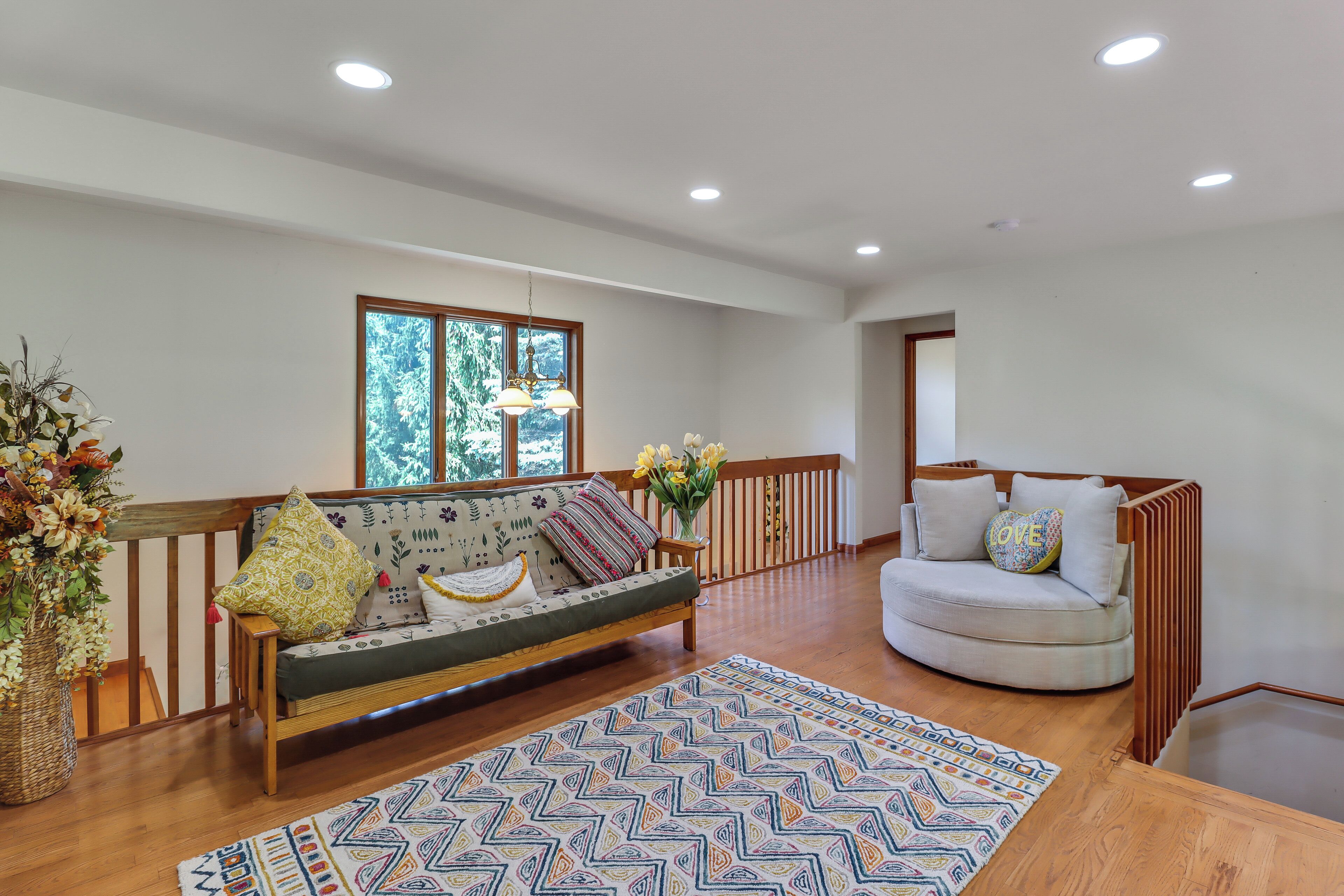 A spacious living area with a sofa, a chair, a patterned rug, and a wooden floor.