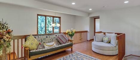 A spacious living area with a sofa, a chair, a patterned rug, and a wooden floor.