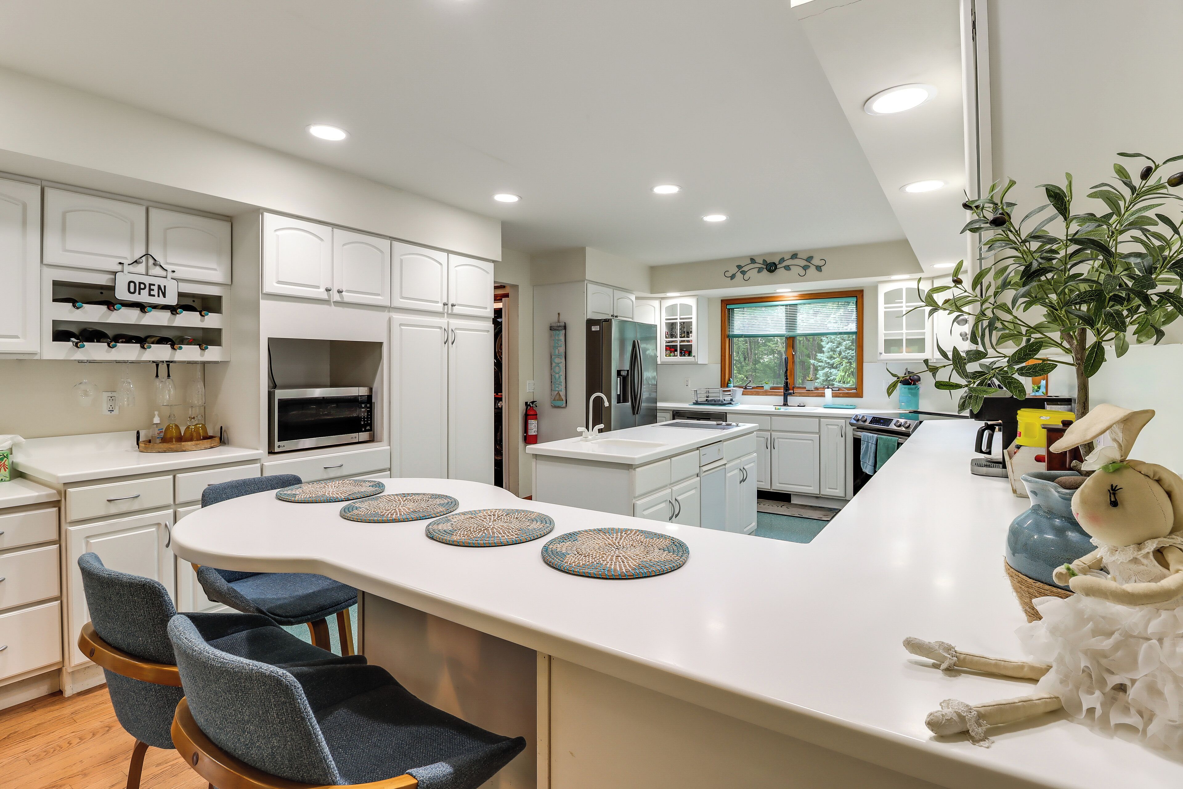 A modern kitchen with white cabinetry, a central island with seating, and a decorative plant.