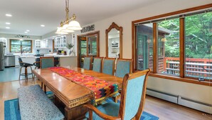 A spacious dining area with a long wooden table, blue upholstered chairs, and a colorful runner.