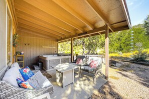 Une terrasse extérieure couverte, équipée d’un barbecue, d’un espace salon et offrant une vue sur la verdure environnante.