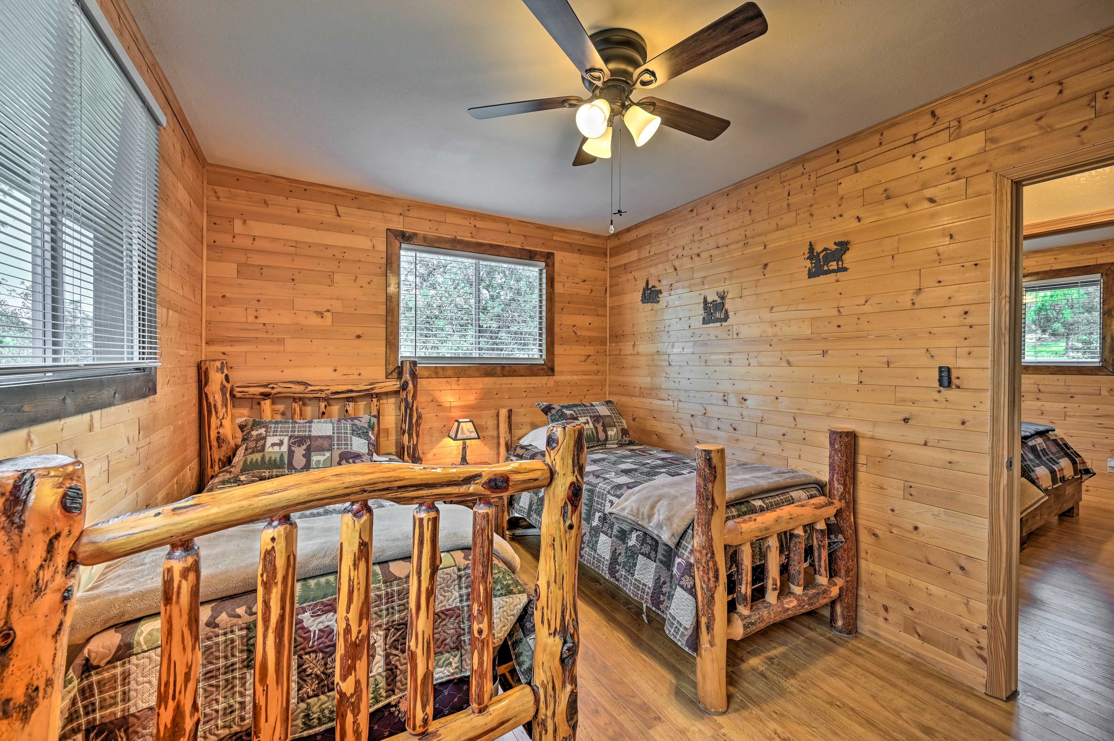 A cabin room with two wooden beds, a ceiling fan, and a window with blinds.