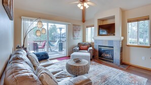 A spacious living room with a leather sofa, a fireplace, and a large window. - Redmond Resort Townhome w/ Private Hot Tub (Redmond)