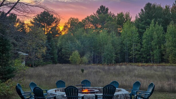 A circular fire pit with chairs around it, set in a natural outdoor area with trees in the background. - 5 Mi to Schuss Mtn: Family Getaway w/ Game Room (Bellaire)