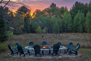 A circular fire pit with chairs around it, set in a natural outdoor area with trees in the background. - 5 Mi to Schuss Mtn: Family Getaway w/ Game Room (Bellaire)