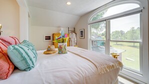 A bedroom with a large window, a bed with white bedding, a basket of colorful items, and a view of the outdoors. - 5 Mi to Schuss Mtn: Family Getaway w/ Game Room (Bellaire)