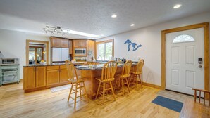 A kitchen with wooden cabinets, a central island with chairs, a microwave, and a refrigerator. - 5 Mi to Schuss Mtn: Family Getaway w/ Game Room (Bellaire)