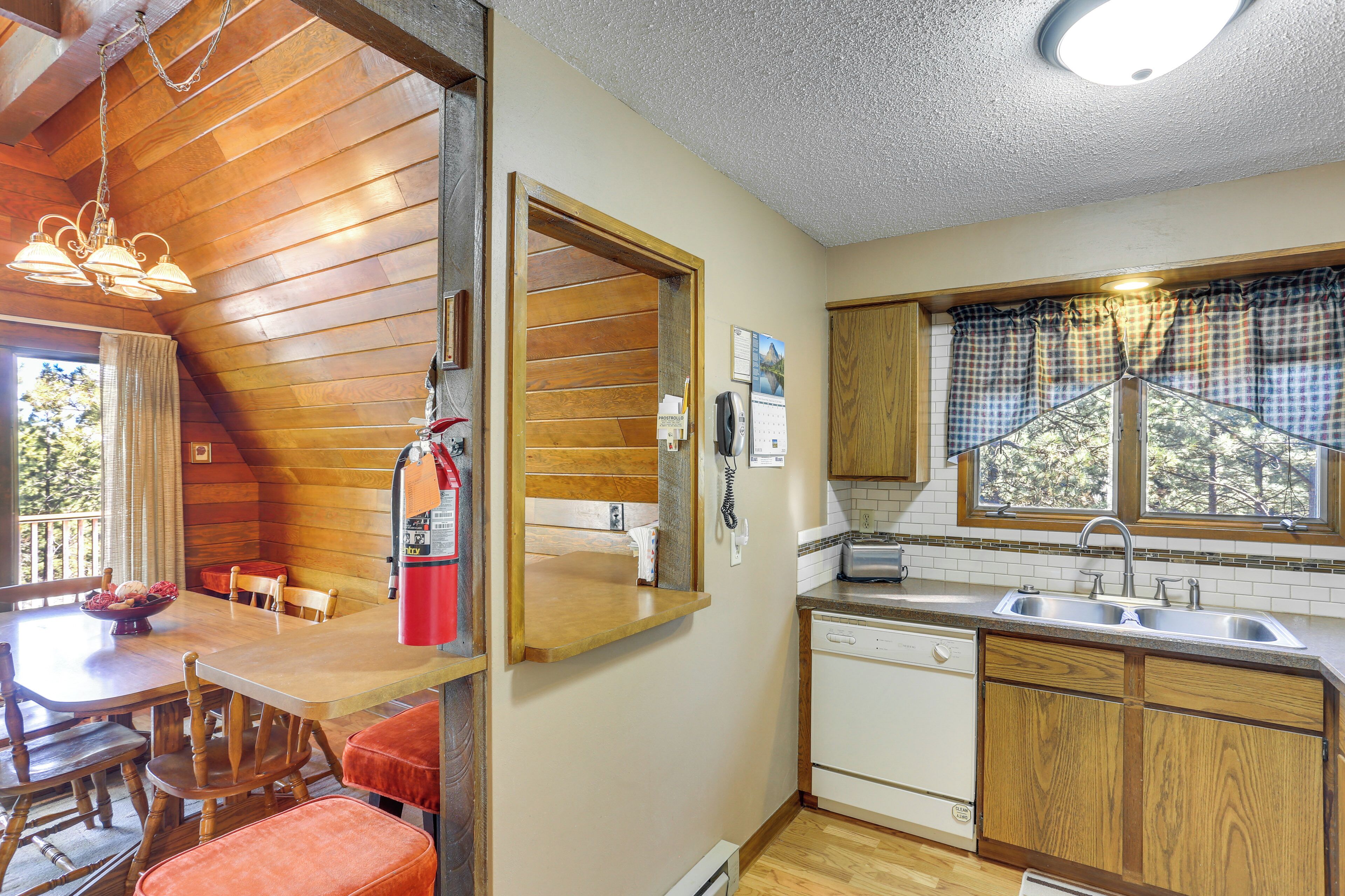 A compact kitchen with wooden cabinets, a sink, and a dining area with a table and chairs.