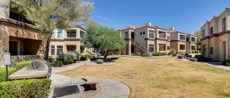 A residential complex with multiple two-story buildings, a central courtyard with a fire pit, and a well-maintained lawn.