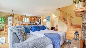 A spacious living area with a large gray sofa, a dining table, and a kitchen in the background.