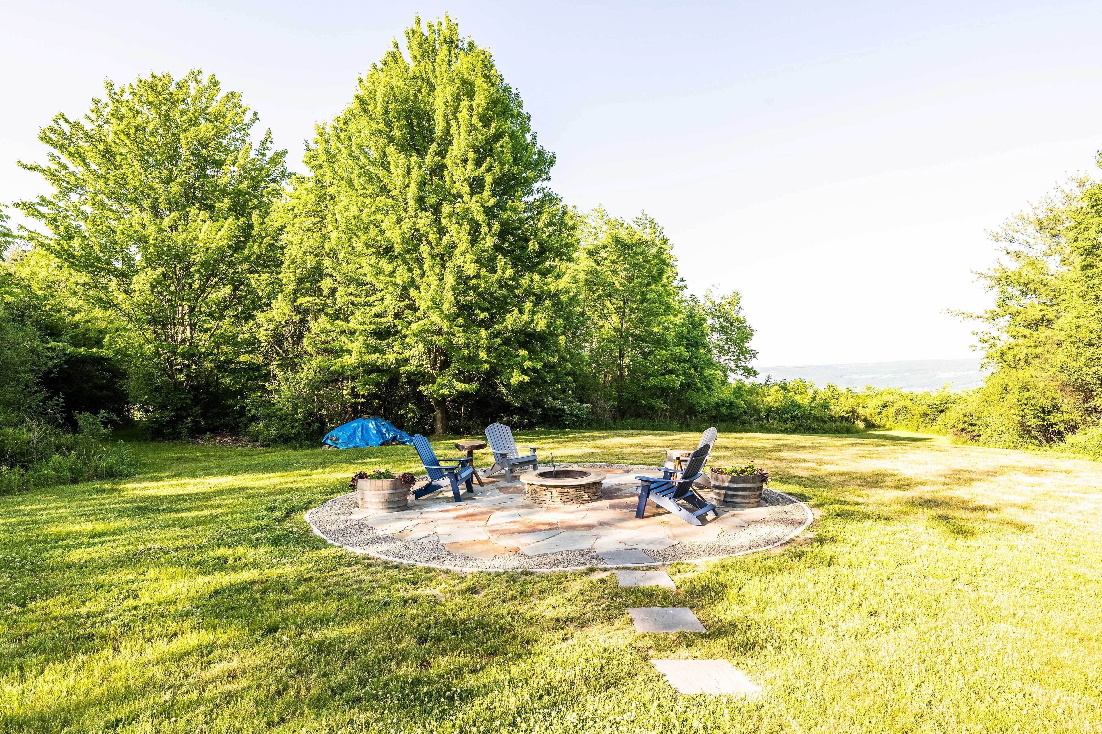 An outdoor patio with a fire pit, seating, and a tent.