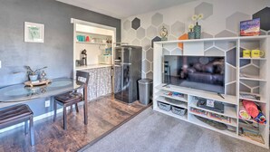 A modern living room with a glass dining table, a sofa, and a TV on a white entertainment unit. - 4 Mi to Beach: Lake Havasu Apartment w/ Pool! (Lake Havasu City)