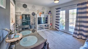 A modern living room with a flat-screen TV, a ceiling fan, and a dining area with a glass table. - 4 Mi to Beach: Lake Havasu Apartment w/ Pool! (Lake Havasu City)