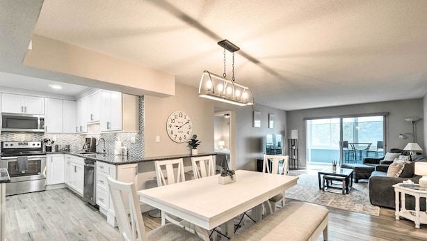 A modern kitchen with white cabinets, a dining area with a white table and chairs, and a living room with a sofa and a coffee table. - Walk to Beach: Resort-style Siesta Key Condo! (Siesta Key)